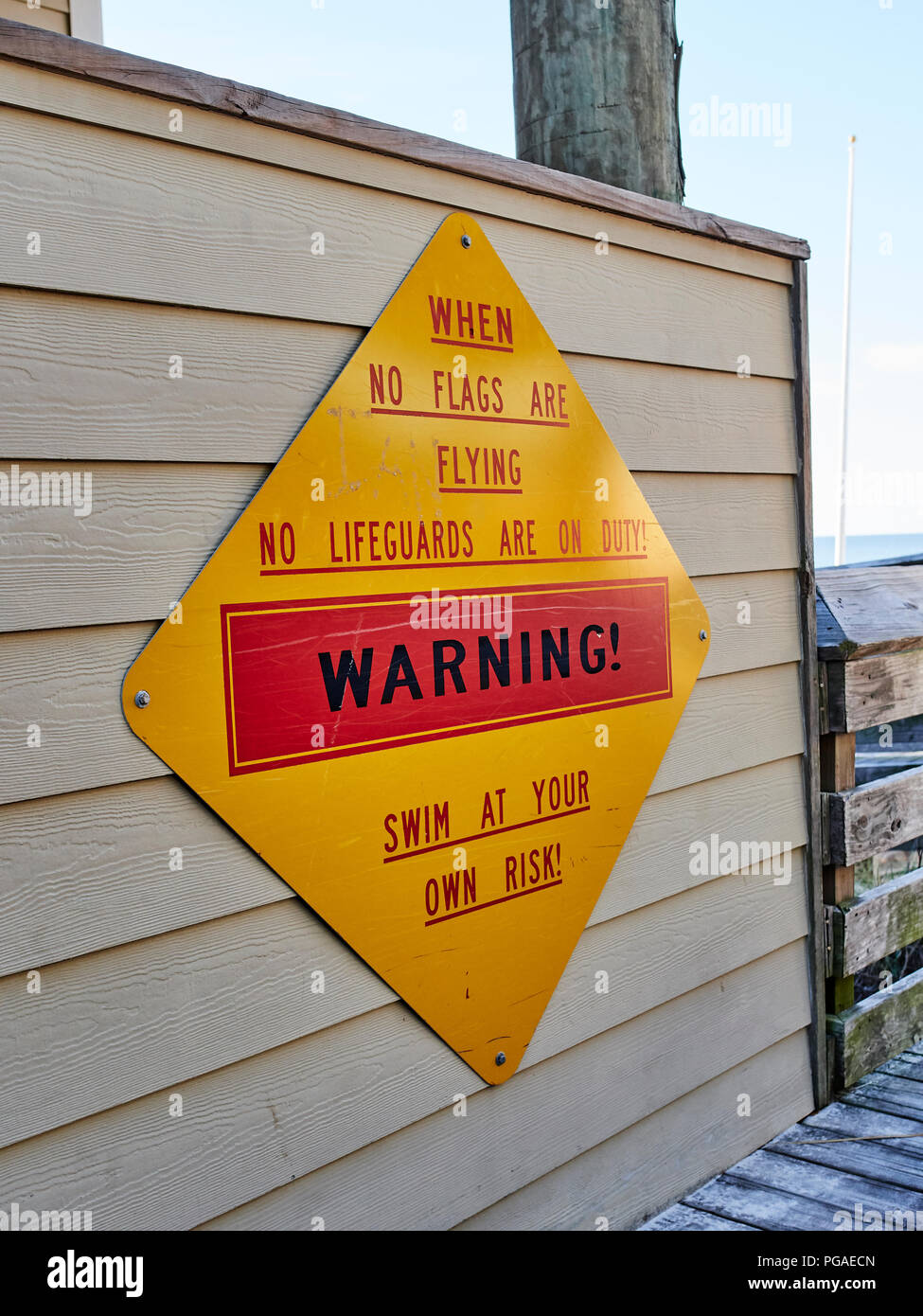 Ocean beach warning sign stating no lifeguard is on duty and to swim at your own risk when no flags are flying in Destin Florida, USA. Stock Photo