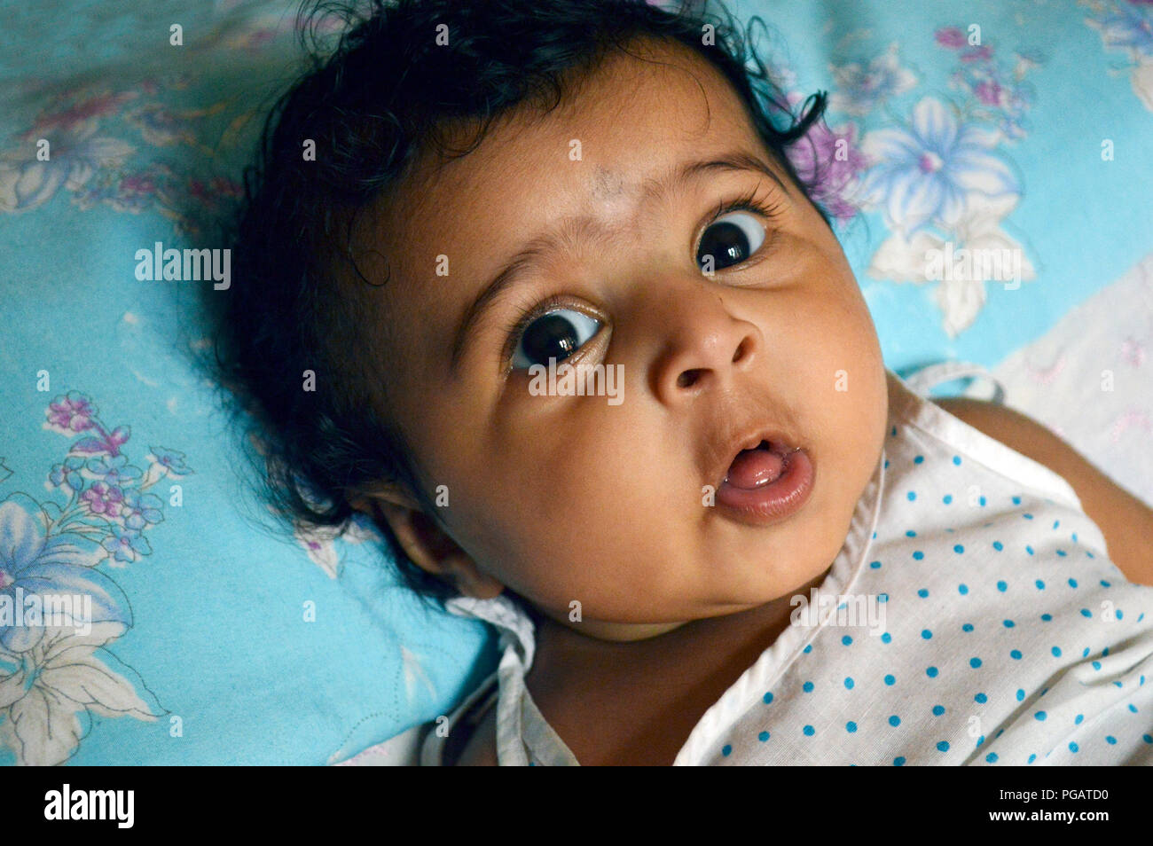 Infant looks at camera with an expression of wonder and surprise with