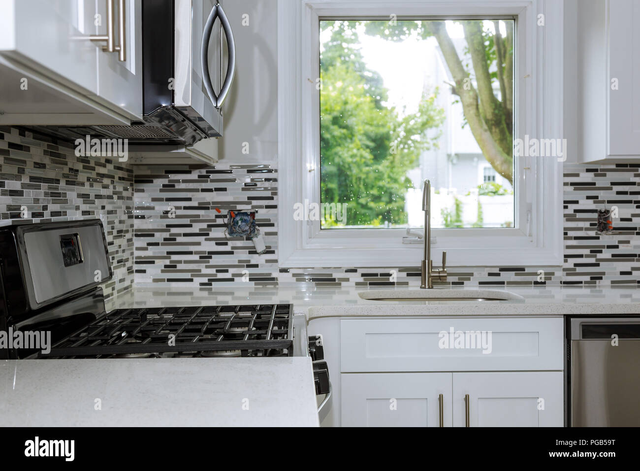 New modern white kitchen Stainless steel sink on the kitchen with built in oven and chrome water tap Stock Photo