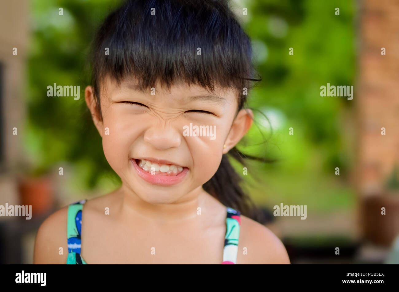 Portrait of an angry girl or girl making face isolated in a blurred natural background Stock Photo