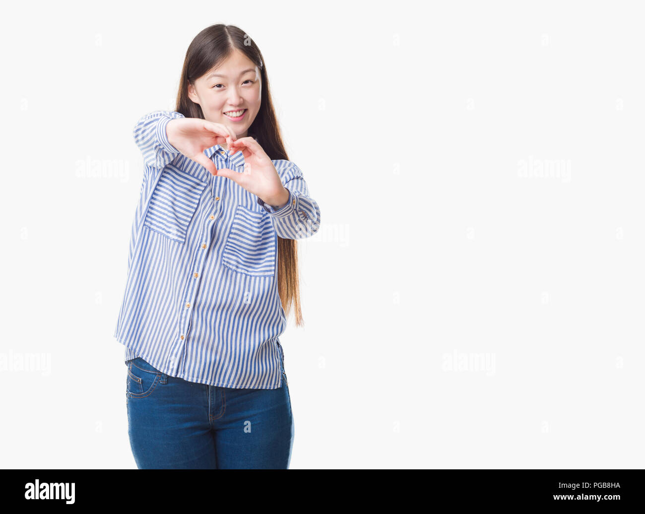 Young Chinese woman over isolated background smiling in love showing heart symbol and shape with hands. Romantic concept. Stock Photo