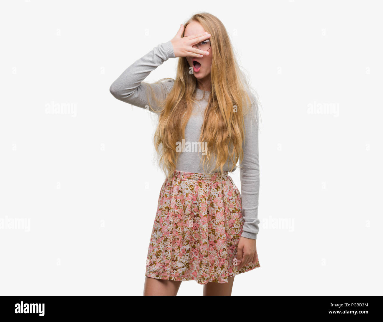 Blonde teenager woman wearing flowers skirt peeking in shock covering face  and eyes with hand, looking through fingers with embarrassed expression  Stock Photo - Alamy