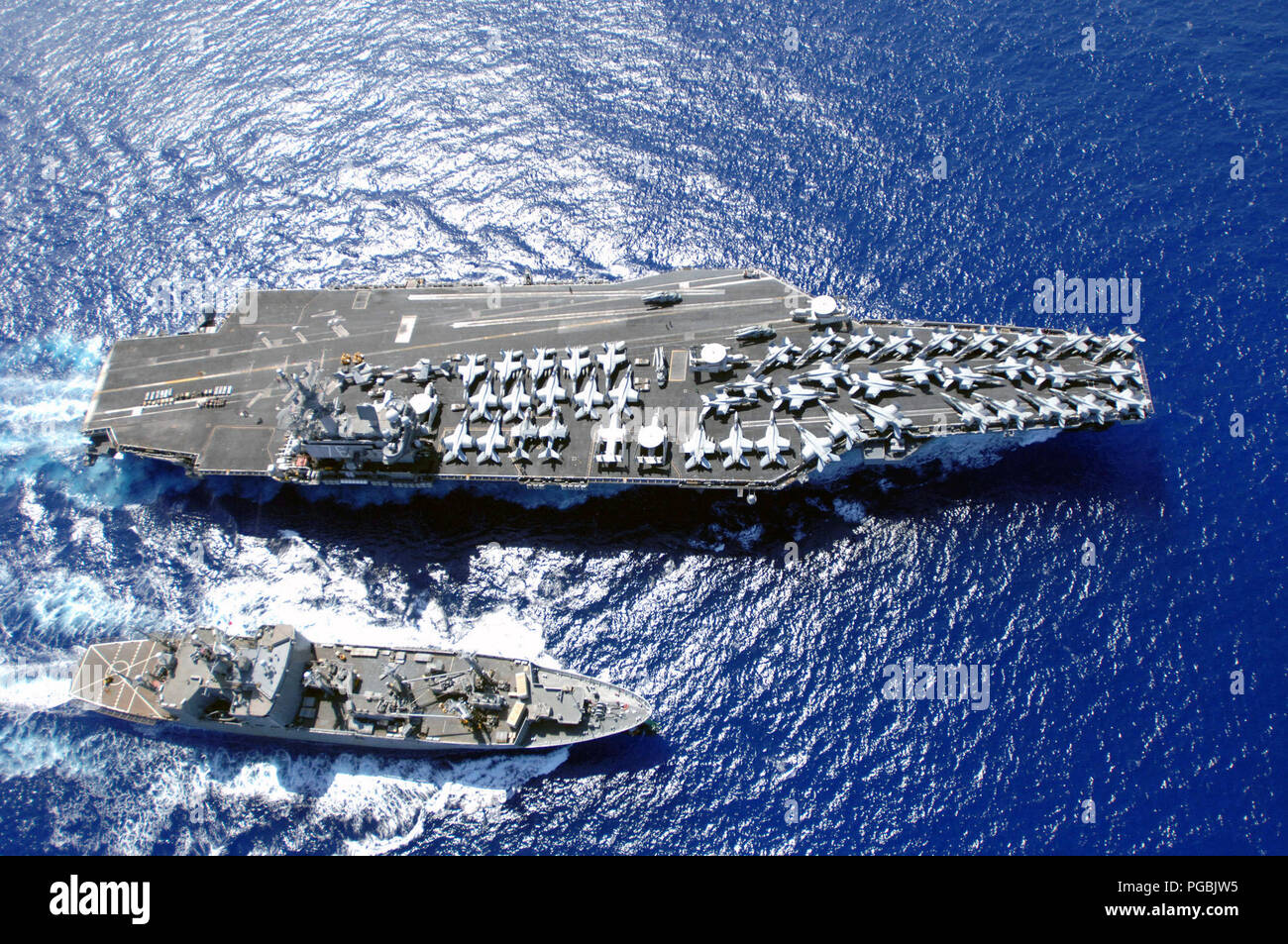 The U.S. Navy Nimitz Class Aircraft Carrier (top) USS RONALD REAGAN (CVN 76) works with the Military Sealift Command Kilauea Class Ammunition Ship (bottom) USNS FLINT (T-AE 32) on April 6, 2007. Stock Photo