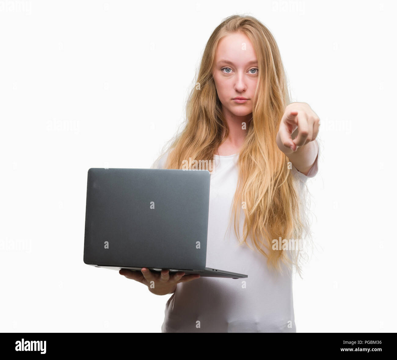Blonde teenager woman using computer laptop pointing with finger to the ...