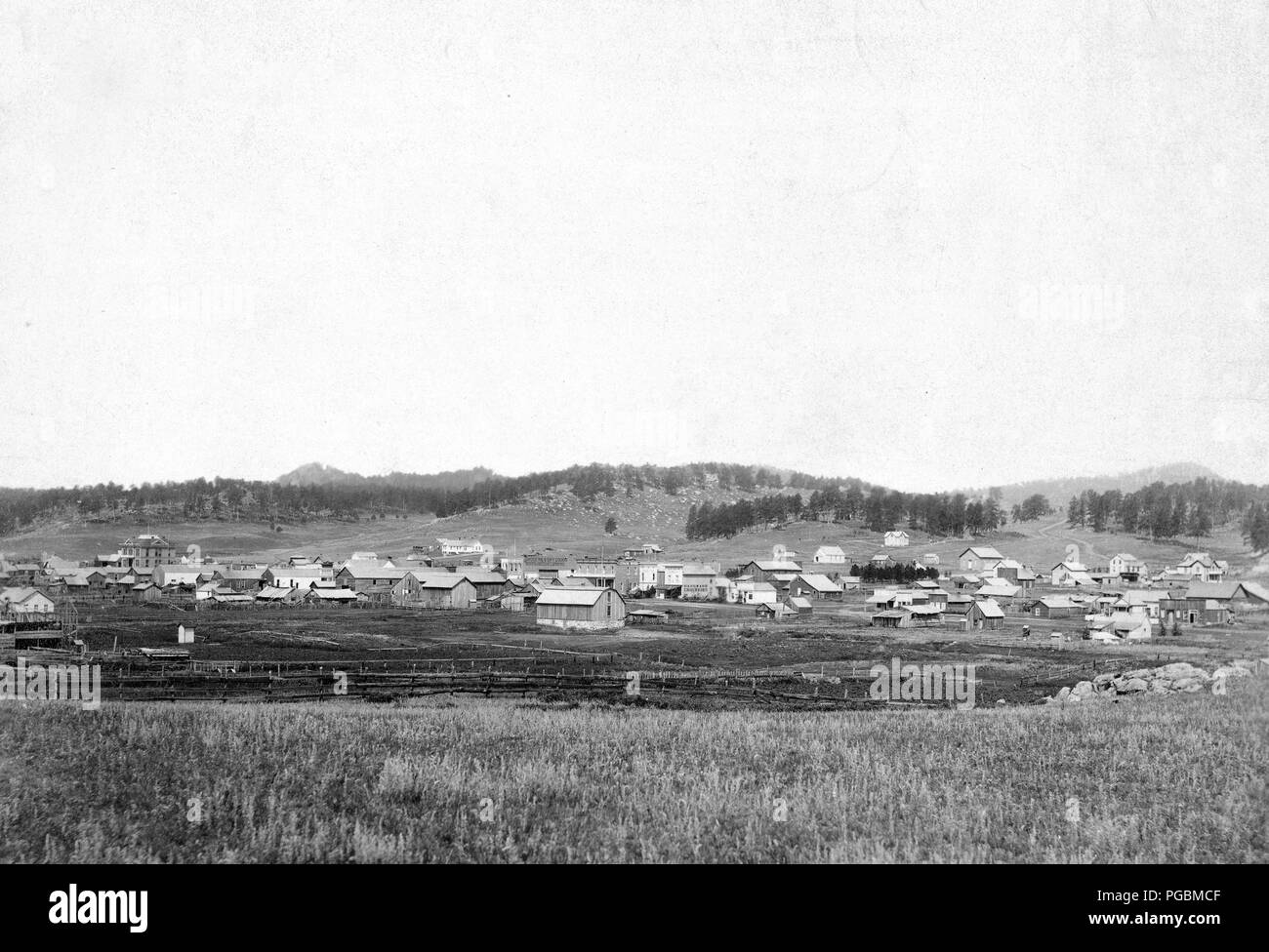 Distant view of small town; field in foreground and hills in background. Stock Photo