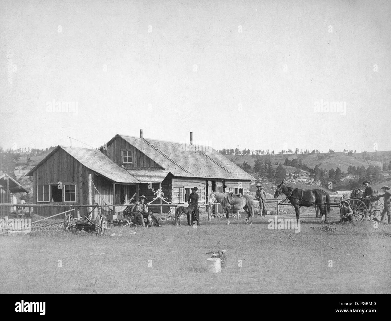 Farm equipment, horses, wagons, dogs, cowboys and others posed in front of western ranch houses Stock Photo