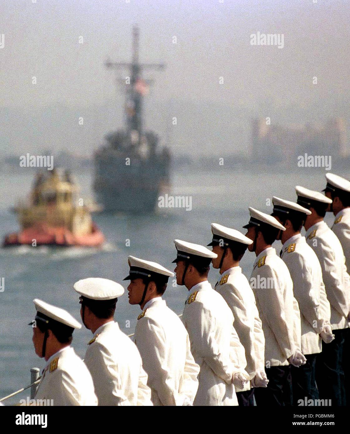 Chinese officers man the rail as the U.S. Navy frigate USS GEORGE PHILLIP (FFG 12) (Out of focus in the background) escorts the Republic of China (Navy) Luhu Class Destroyer, HARIBING (DDG 112), into San Diego Bay. This marks the first time Chinese warships have crossed the Pacific and visited the Continental United States.  The destroyer HARIBING, Luda II Class Destroyer, ZHUHAI (DDG 166), and a supply ship, the Fusu Class, NANYUN (AOR/AK 953), (ZHUHAI and NANYUN not shown) stopped at Naval Station, North Island, San Diego, California, on March 21st, 1997. Stock Photo
