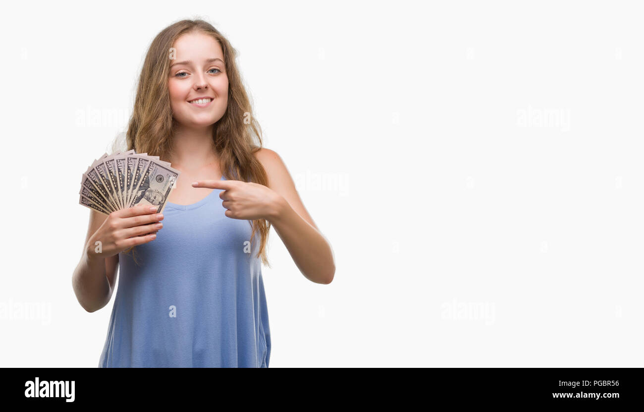 Young blonde woman holding dollars very happy pointing with hand and finger Stock Photo