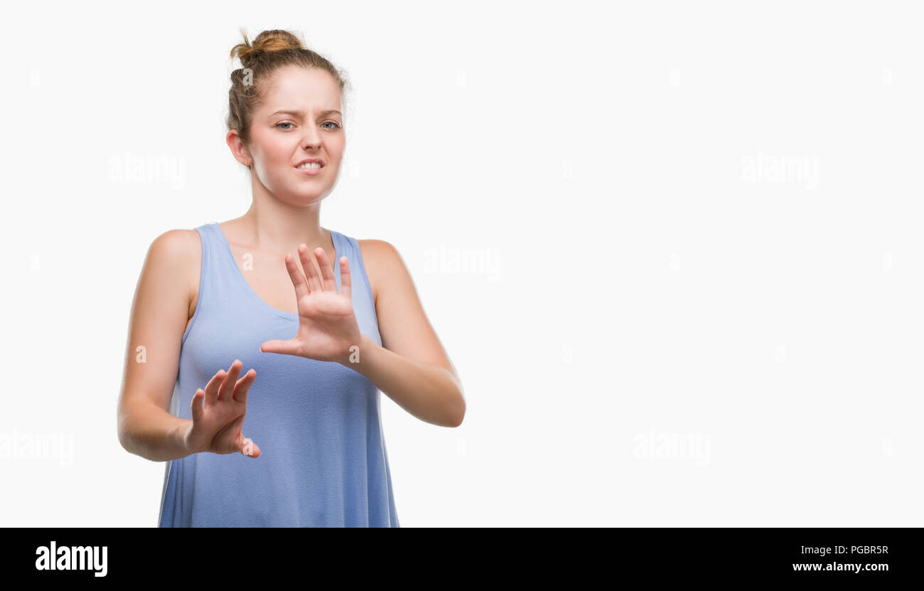 Young blonde woman disgusted expression, displeased and fearful doing disgust face because aversion reaction. With hands raised. Annoying concept. Stock Photo
