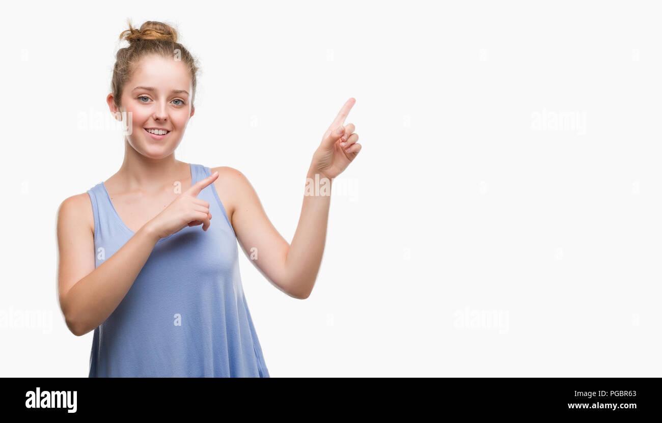 Young blonde woman smiling and looking at the camera pointing with two hands and fingers to the side. Stock Photo