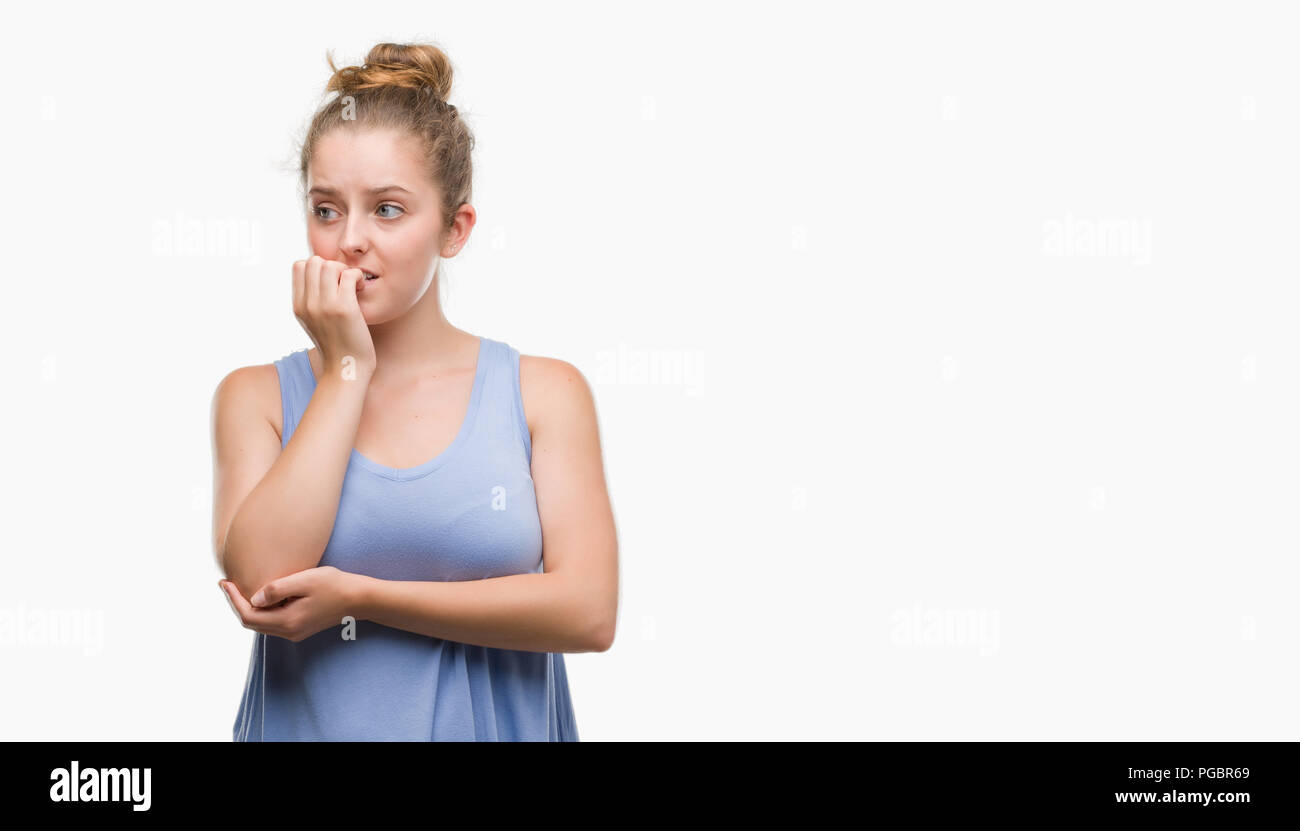 Young blonde woman looking stressed and nervous with hands on mouth biting nails. Anxiety problem. Stock Photo