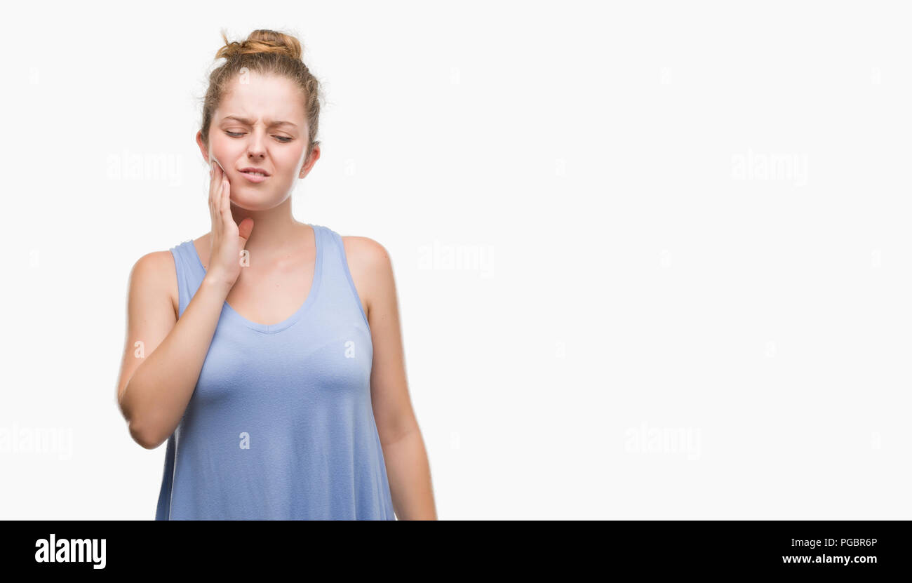 Young blonde woman touching mouth with hand with painful expression because of toothache or dental illness on teeth. Dentist concept. Stock Photo