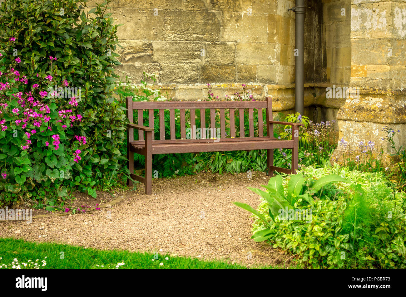 Quiet seat among the flowerbeds against a stone wall. Stock Photo