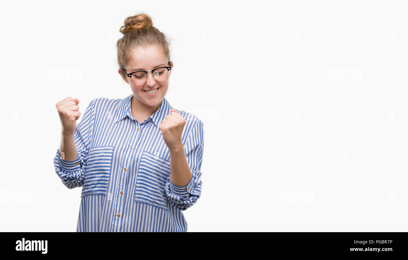 Young blonde business woman very happy and excited doing winner gesture with arms raised, smiling and screaming for success. Celebration concept. Stock Photo