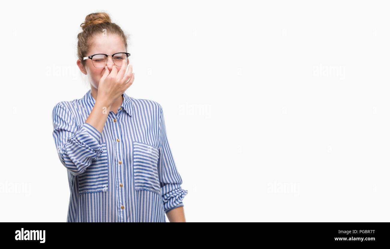 Young blonde business woman smelling something stinky and disgusting, intolerable smell, holding breath with fingers on nose. Bad smells concept. Stock Photo