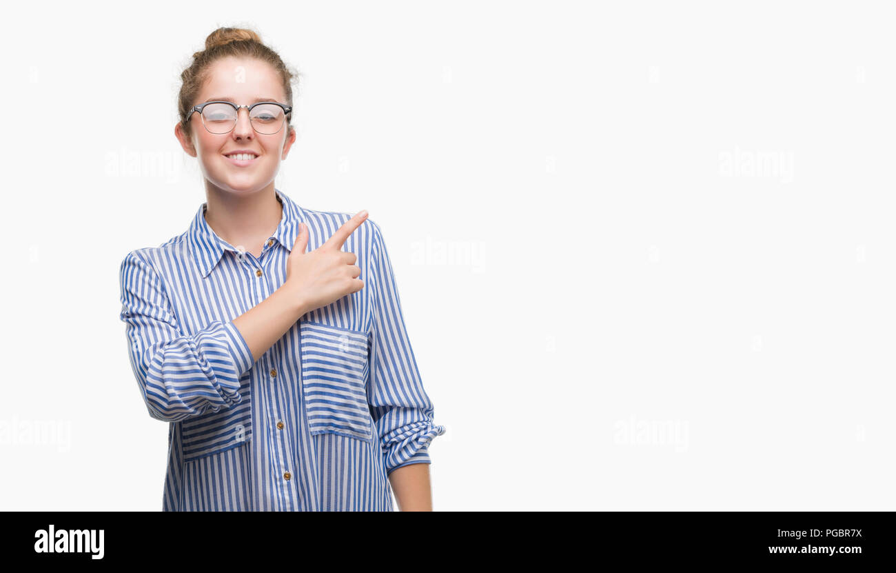Young blonde business woman cheerful with a smile of face pointing with hand and finger up to the side with happy and natural expression on face looki Stock Photo