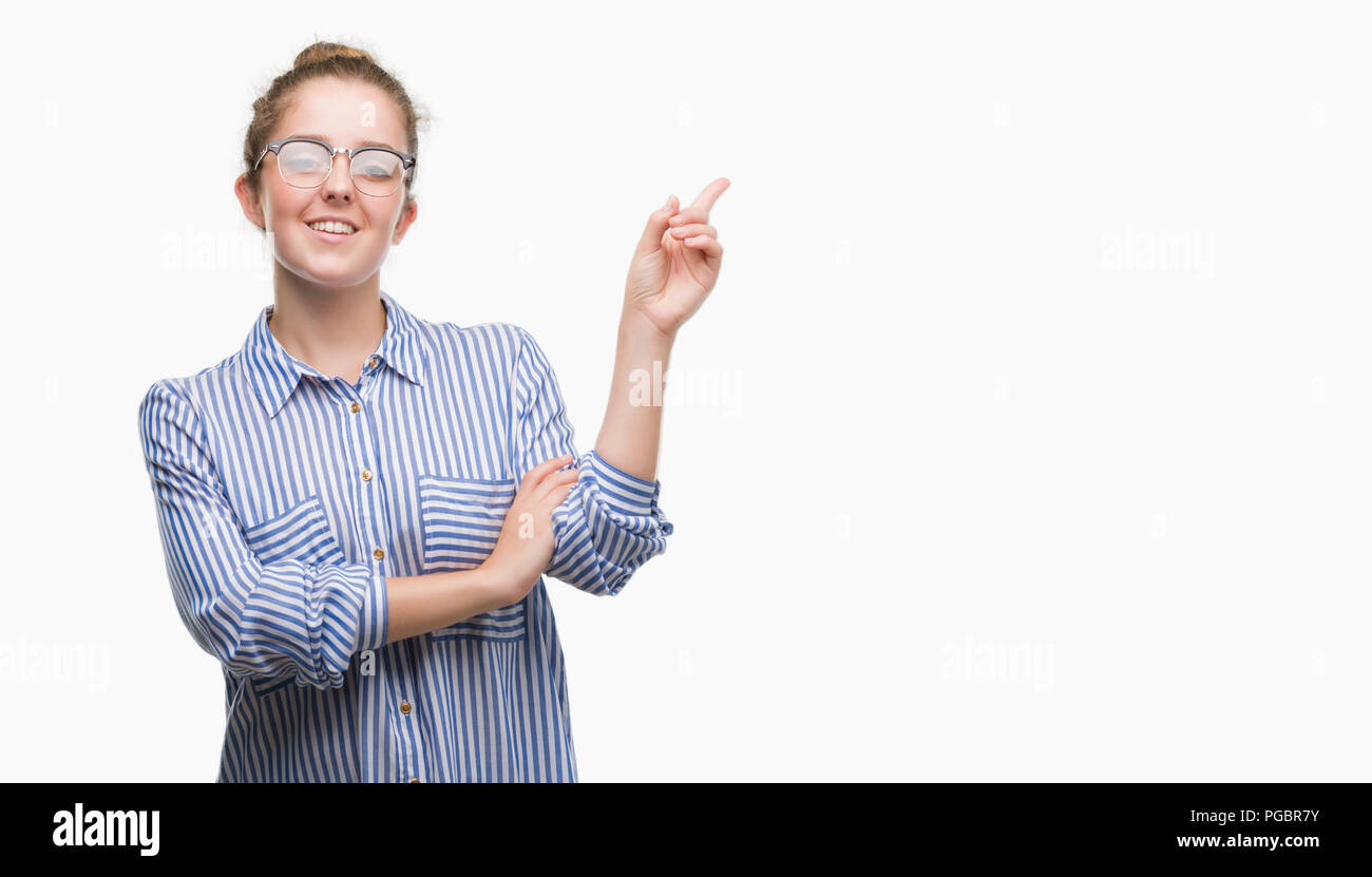 Young blonde business woman with a big smile on face, pointing with hand and finger to the side looking at the camera. Stock Photo