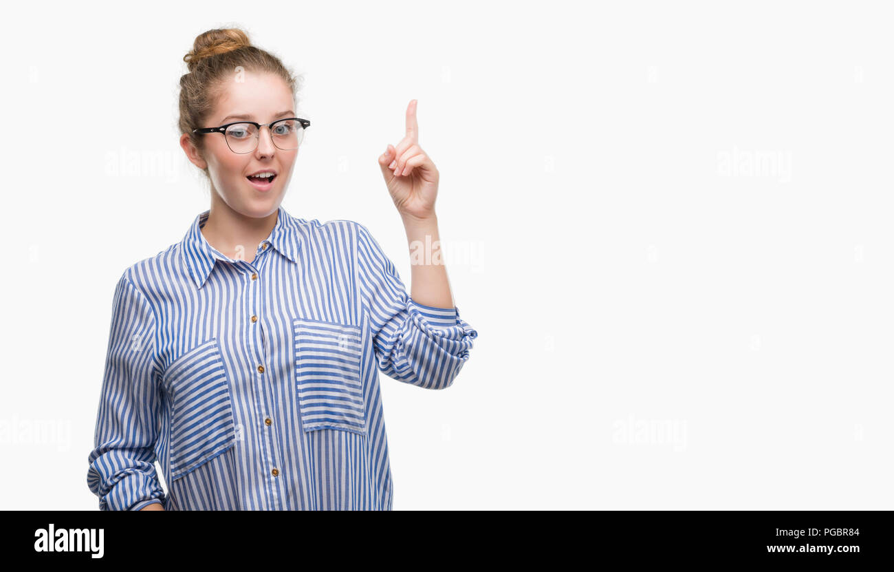 Young blonde business woman pointing finger up with successful idea. Exited and happy. Number one. Stock Photo