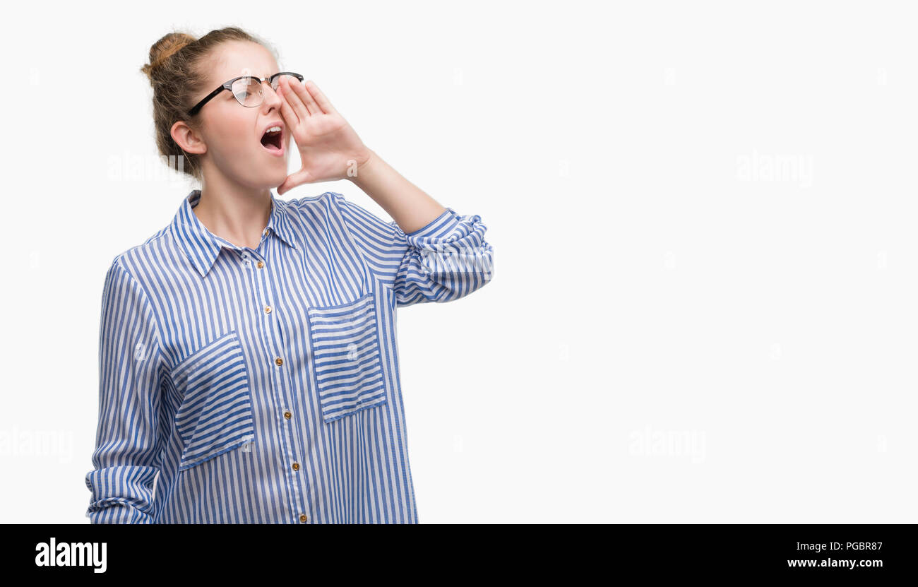 Young blonde business woman shouting and screaming loud to side with hand on mouth. Communication concept. Stock Photo