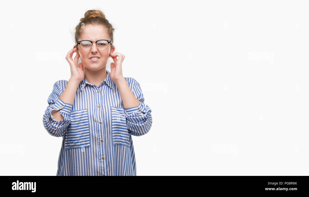 Young blonde business woman covering ears with fingers with annoyed expression for the noise of loud music. Deaf concept. Stock Photo