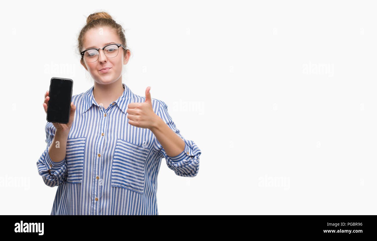 Young blonde woman using smartphone happy with big smile doing ok sign, thumb up with fingers, excellent sign Stock Photo