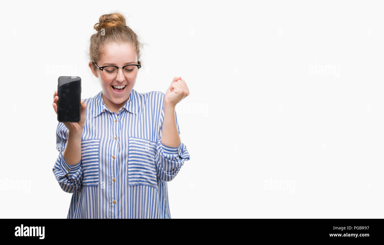 Young blonde woman using smartphone screaming proud and celebrating victory and success very excited, cheering emotion Stock Photo