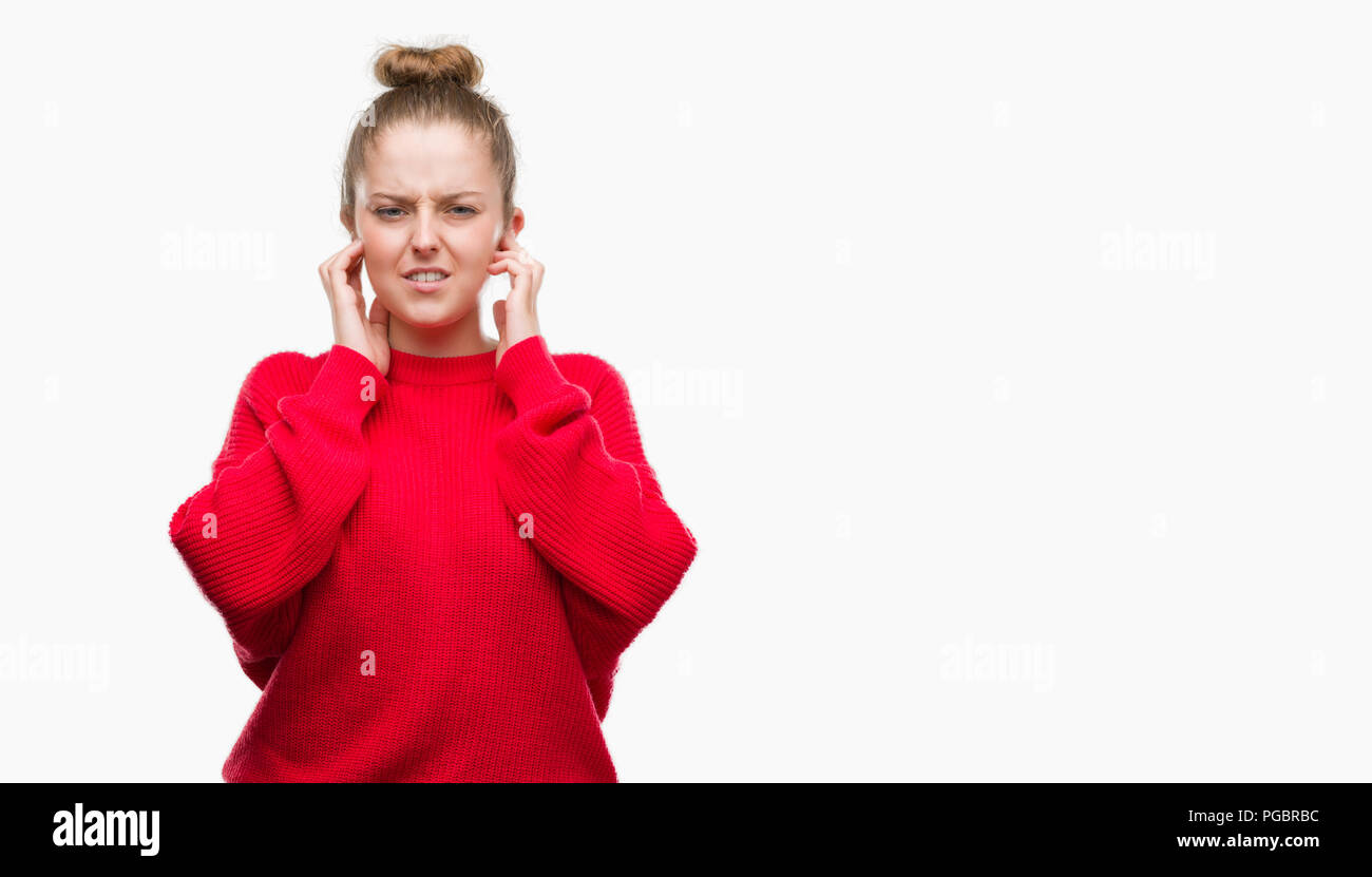 Young Blonde Woman Wearing Bun And Red Sweater Covering Ears With Fingers With Annoyed 