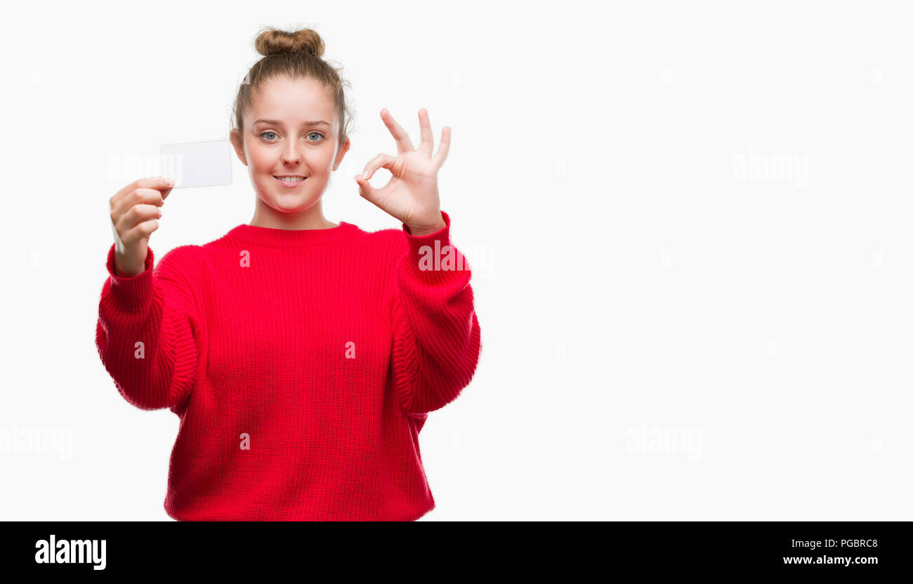 Young blonde woman holding advertising card doing ok sign with fingers, excellent symbol Stock Photo
