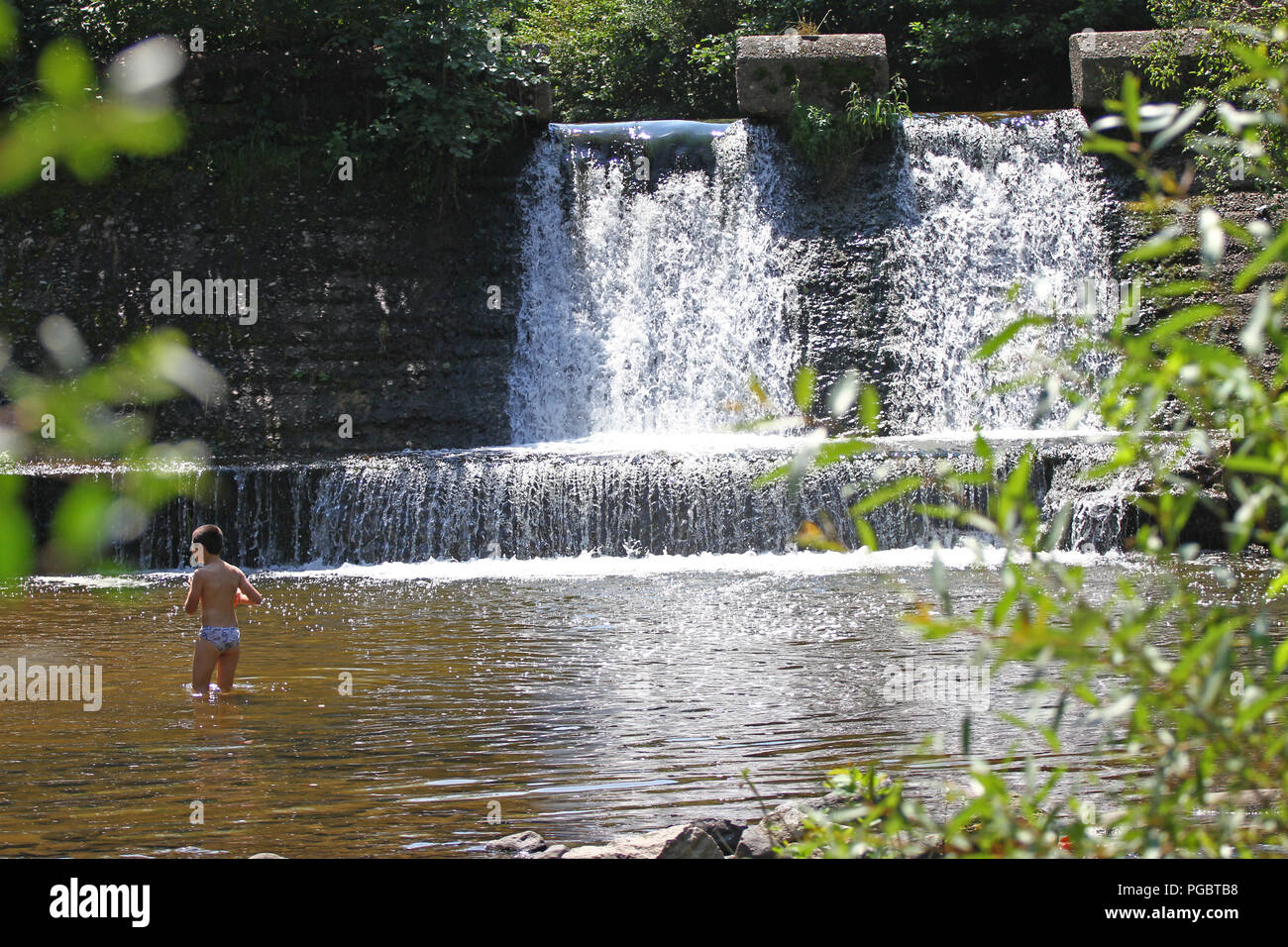 Children play in an unguarded pool on a hot sunny day in the nature. Kids  swim in unsave river on a unhealthy sunlight. Children play danger game in  d Stock Photo -