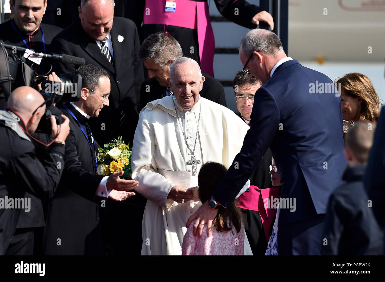 Pope Francis is greeted by Simon Coveney, Irish Minister for Foreign Affairs and his daughters as he arrives at Dublin Airport as he arrives at Dublin Airport as he arrives at Dublin International Airport, at the start of his visit to Ireland. Stock Photo