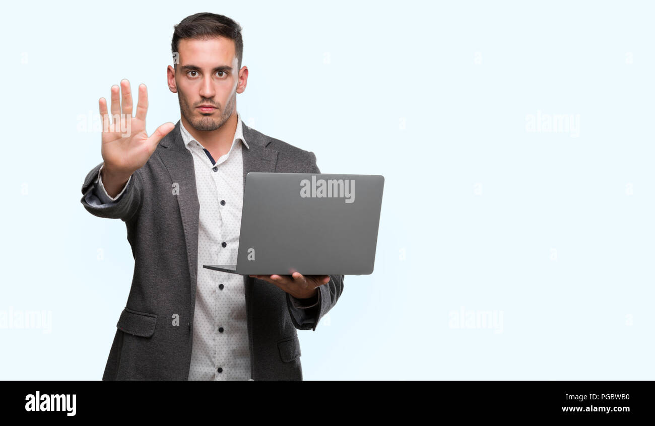 Man With Left Hand Computer Handsome young man using computer laptop with open hand doing stop sign ...