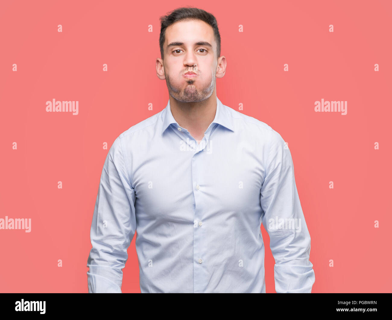 Handsome young businessman puffing cheeks with funny face. Mouth