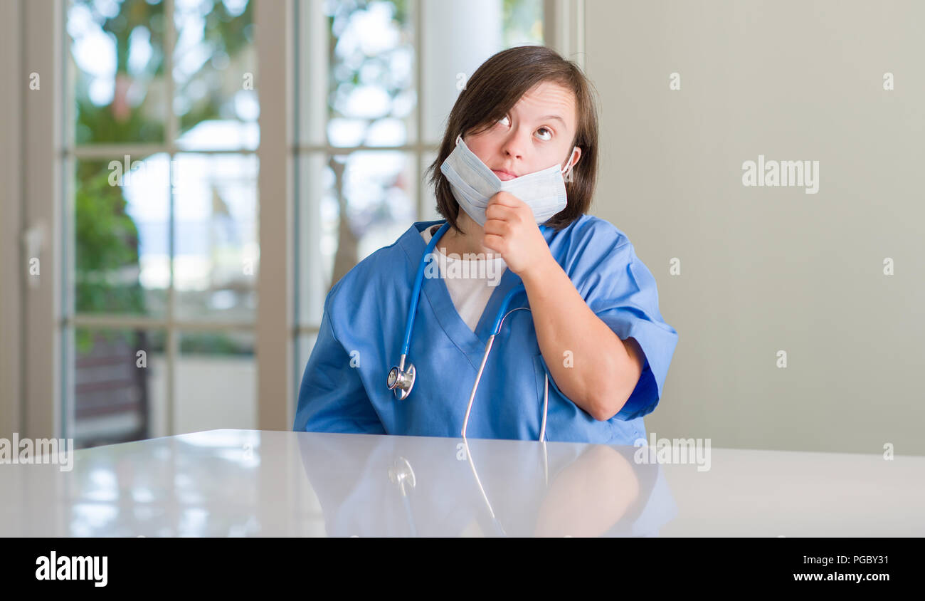 Down syndrome woman wearing nurse uniform serious face thinking about