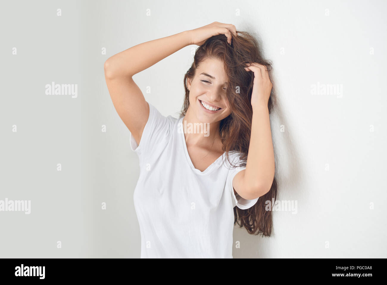 Young smiling playful blond woman holding her hair while leaning ...