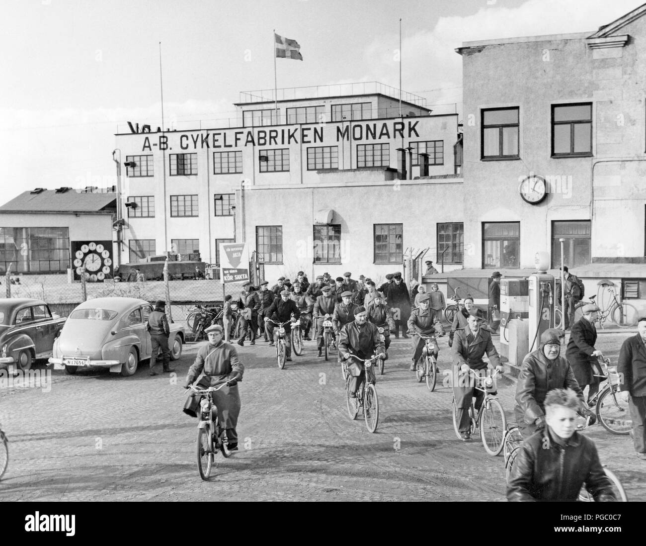 Factory in the 1950s. Work is over for the day at the bicycle and motorcycle company Monark in Sweden. The workers are leaving the factory building on their bicycles and mopeds. Sweden 1958 Stock Photo