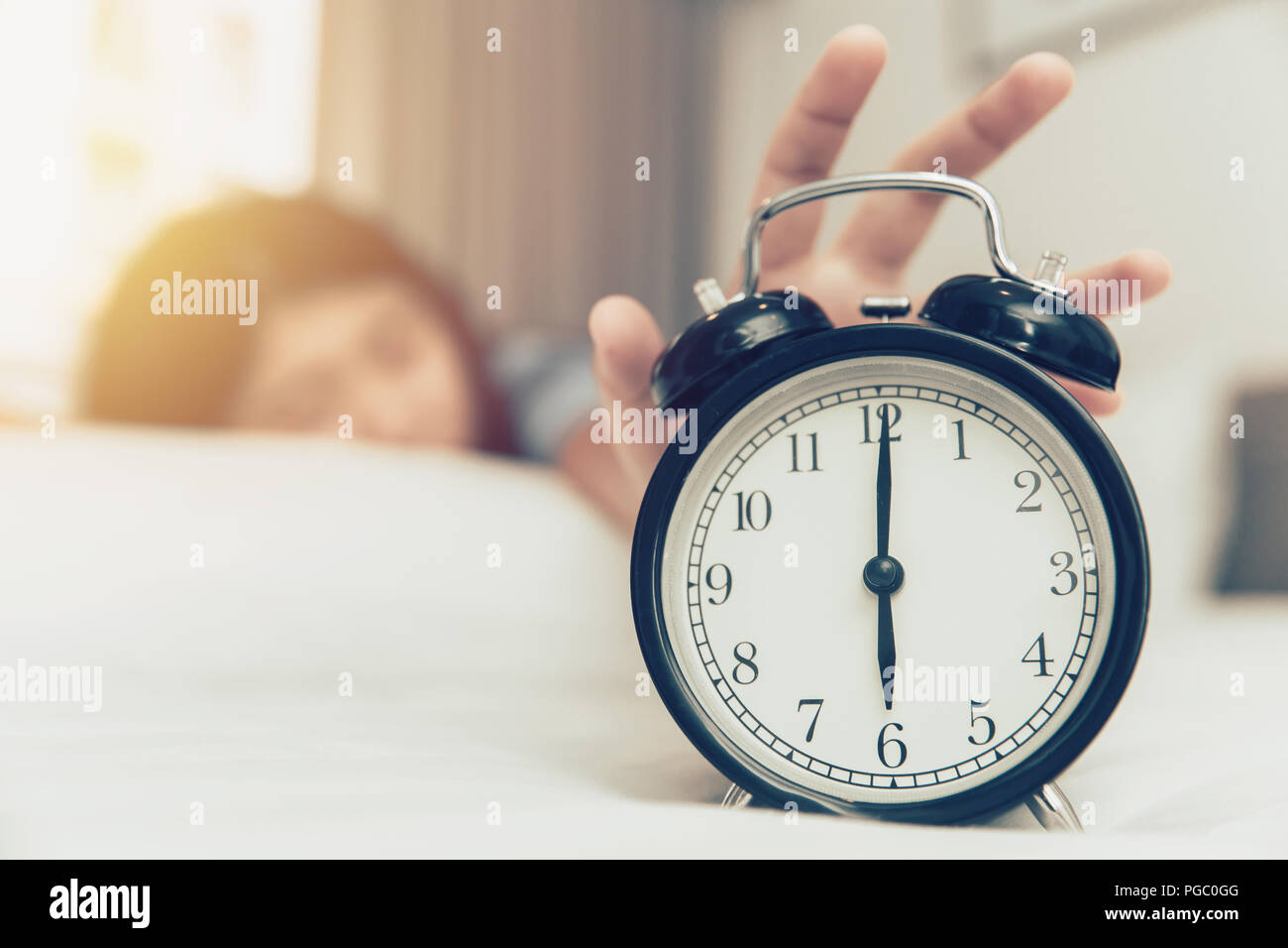 lazy to wake up girl hand off alarm clock ring on bed at morning monday Stock Photo