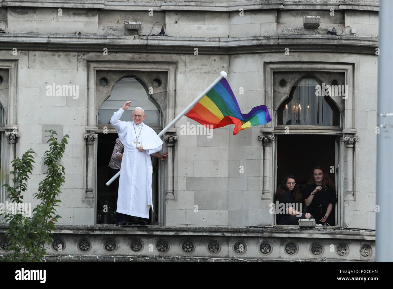 A rainbow flag is flown next to a likeness of Pope Francis as crowds wait on Christchurch, Dublin for the pope to arrive in the Popemobile as he is driven through Dublin during his visit to Ireland. Stock Photo