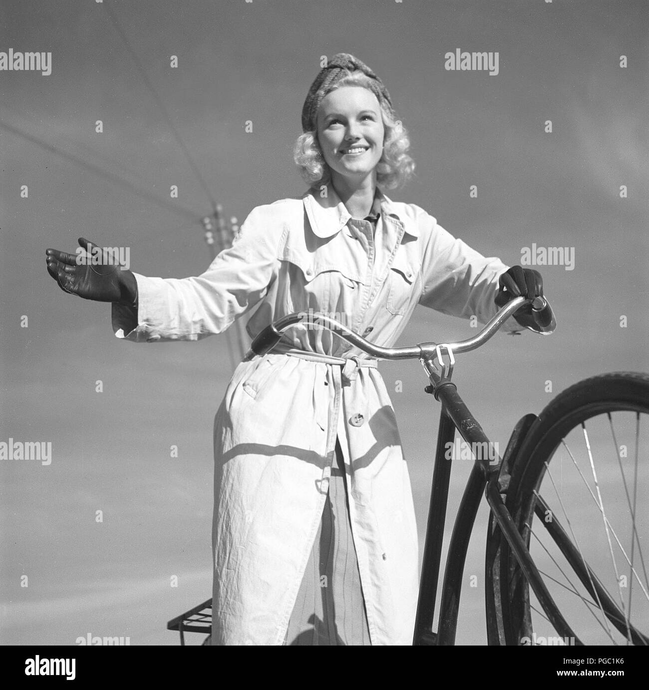 1940s woman on a bicycle. The Swedish actress Karin Nordgren is holding out her hand to give sign that she will turn right. Sweden 1940. Photo Kristoffersson 157-12 Stock Photo