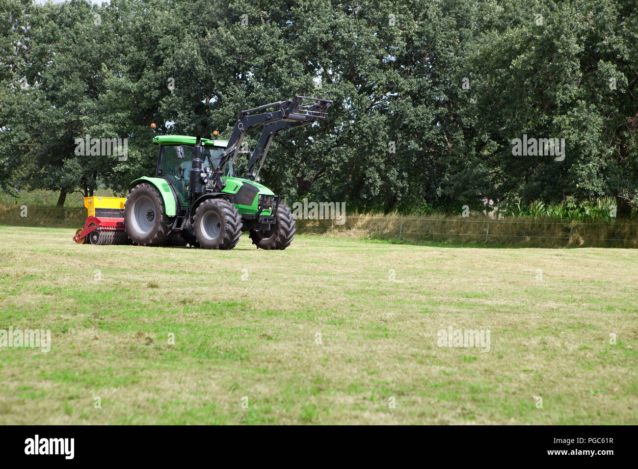 a modern tractor works the turf on a horse pasture Stock Photo