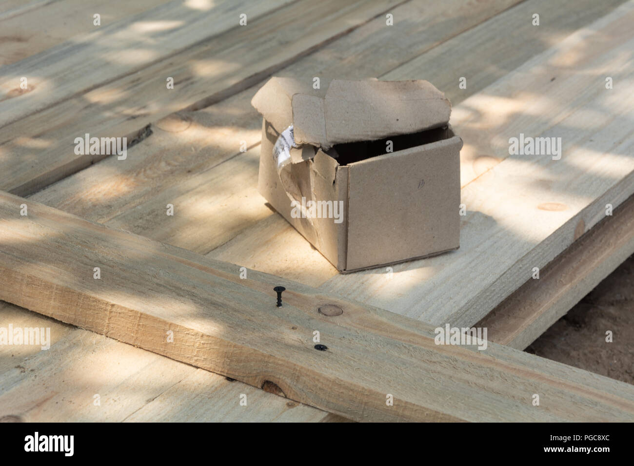 A box of screws on a wooden surface, a formwork for a fence Stock Photo