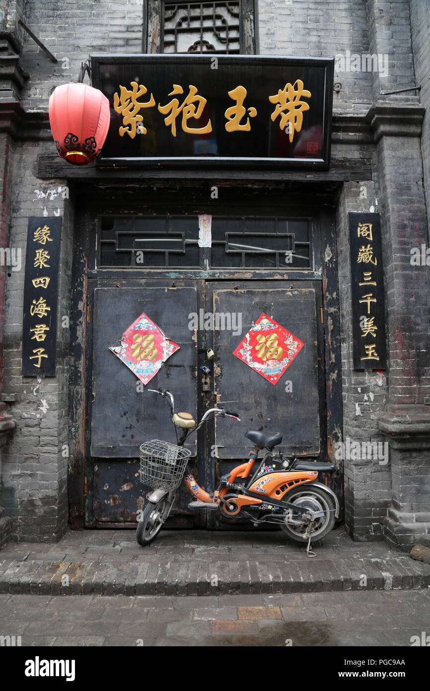 Door of a traditional house in Pingyao, China, with motorbike and Chinese writings Stock Photo