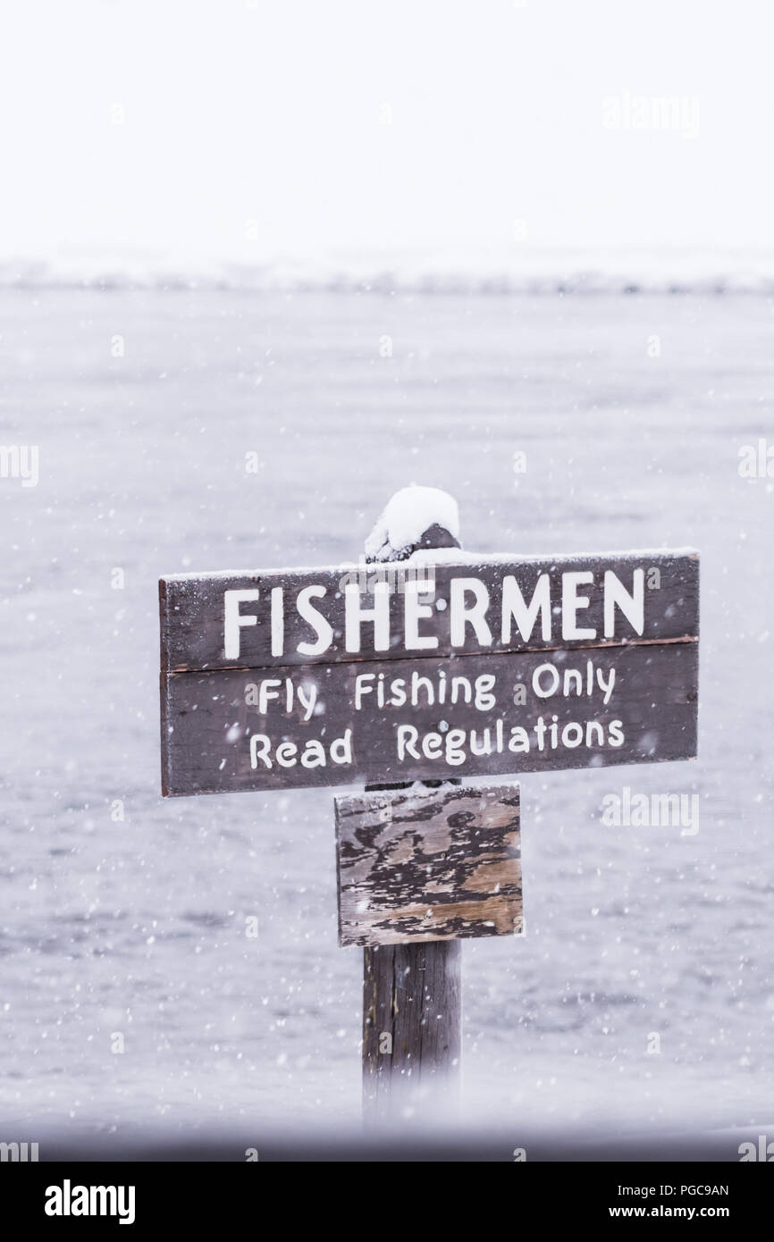A snow covered sign warns fishermen that only Fly Fishing is allowed in this part of the river in Yellowstone National Park, Wyoming, USA. Stock Photo