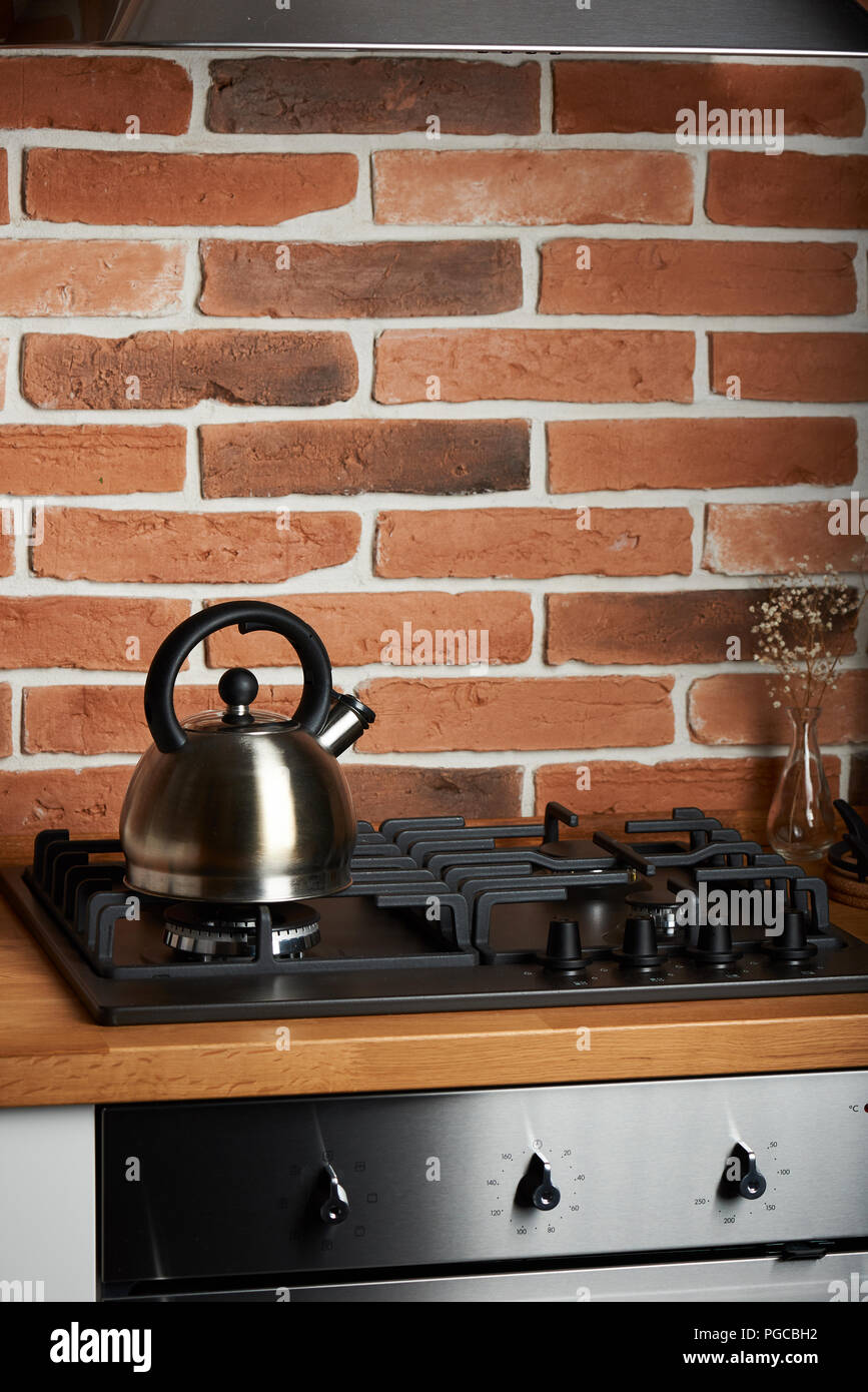 Stainless kettle on stove in modern kitchen background Stock Photo