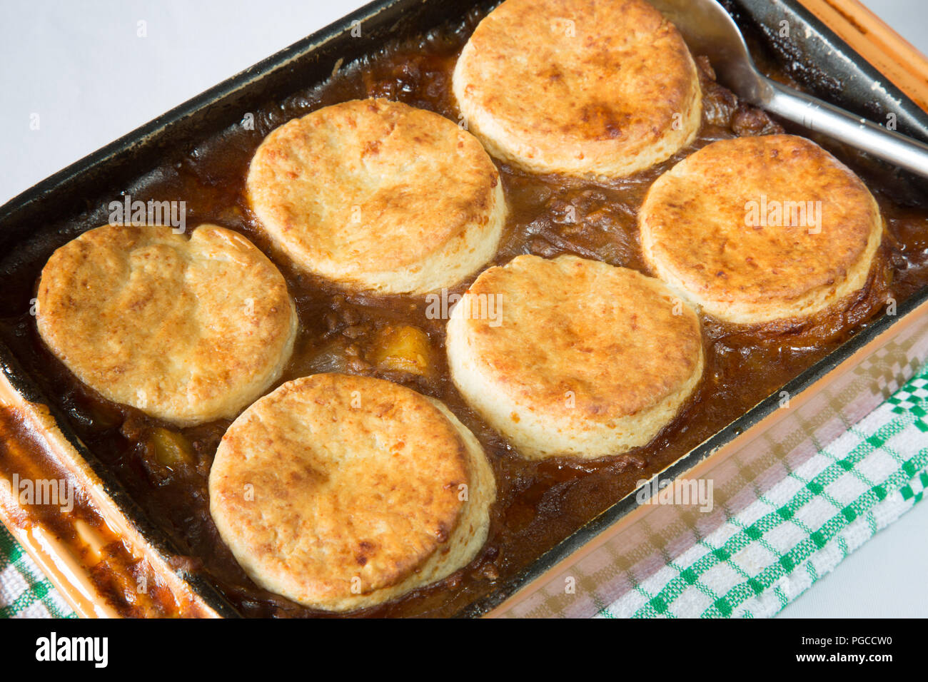 Savoury/Savory minced Beef stew topped with cheese scones in an oven proof roasting dish. Beef cobbler Stock Photo