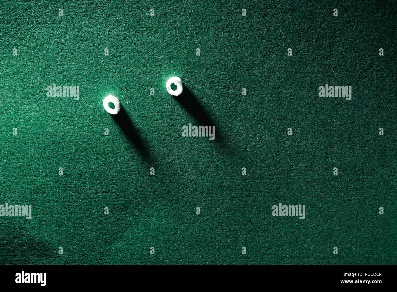 Spying concept. Pair of eyes looking from green paper wall Stock Photo