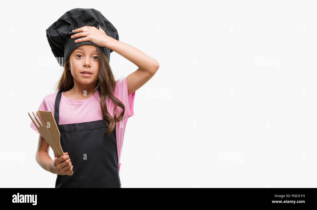 Brunette hispanic girl wearing cook uniform stressed with hand on head, shocked with shame and surprise face, angry and frustrated. Fear and upset for Stock Photo