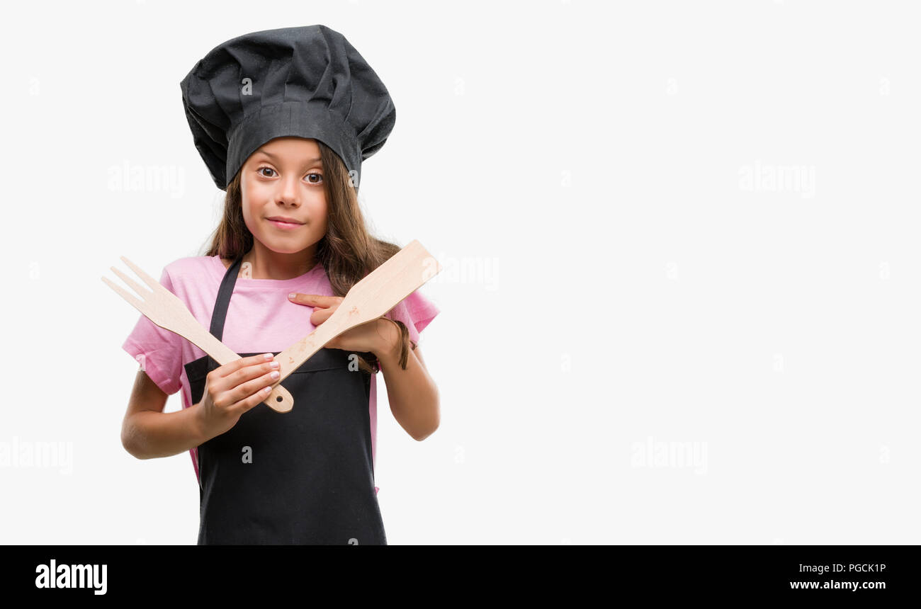 Brunette hispanic girl wearing cook uniform with surprise face pointing finger to himself Stock Photo