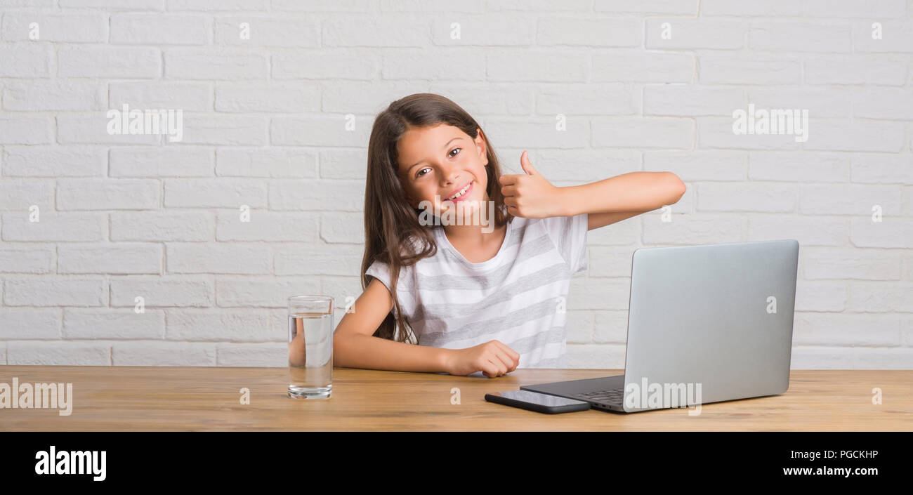 Young Hispanic Kid Sitting On The Table Using Computer Laptop