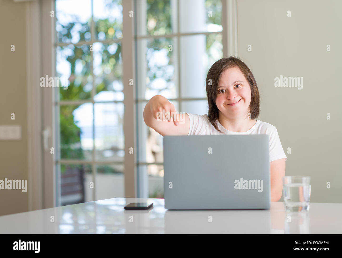 Down syndrome woman at home using computer laptop very happy pointing ...