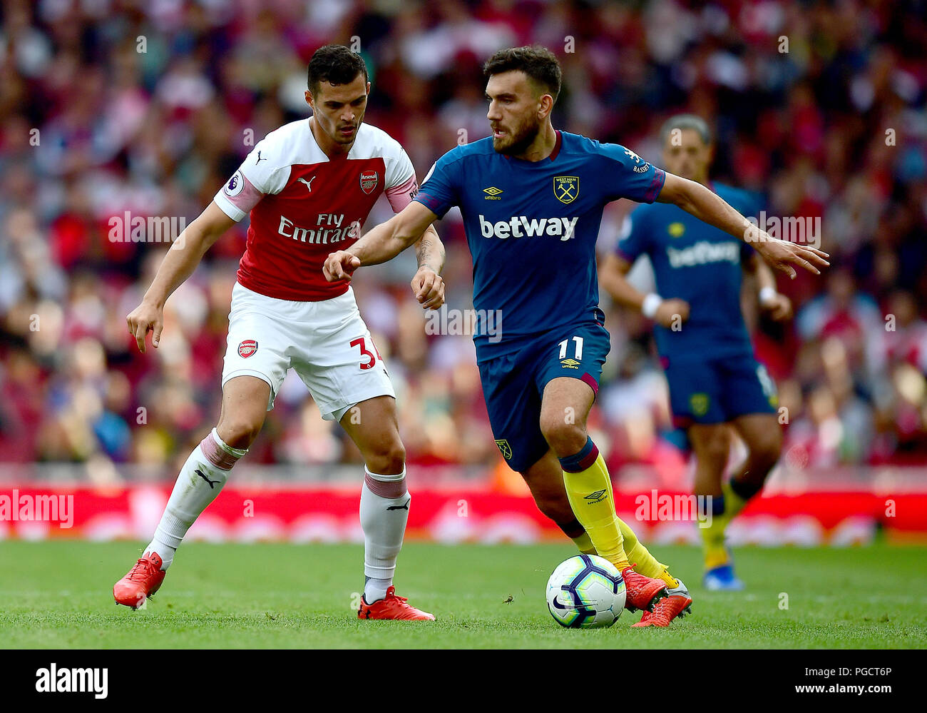 Arsenal's Granit Xhaka (left) and West Ham United's Robert Snodgrass (right) battle for the ball during the Premier League match at the Emirates Stadium, London. Stock Photo